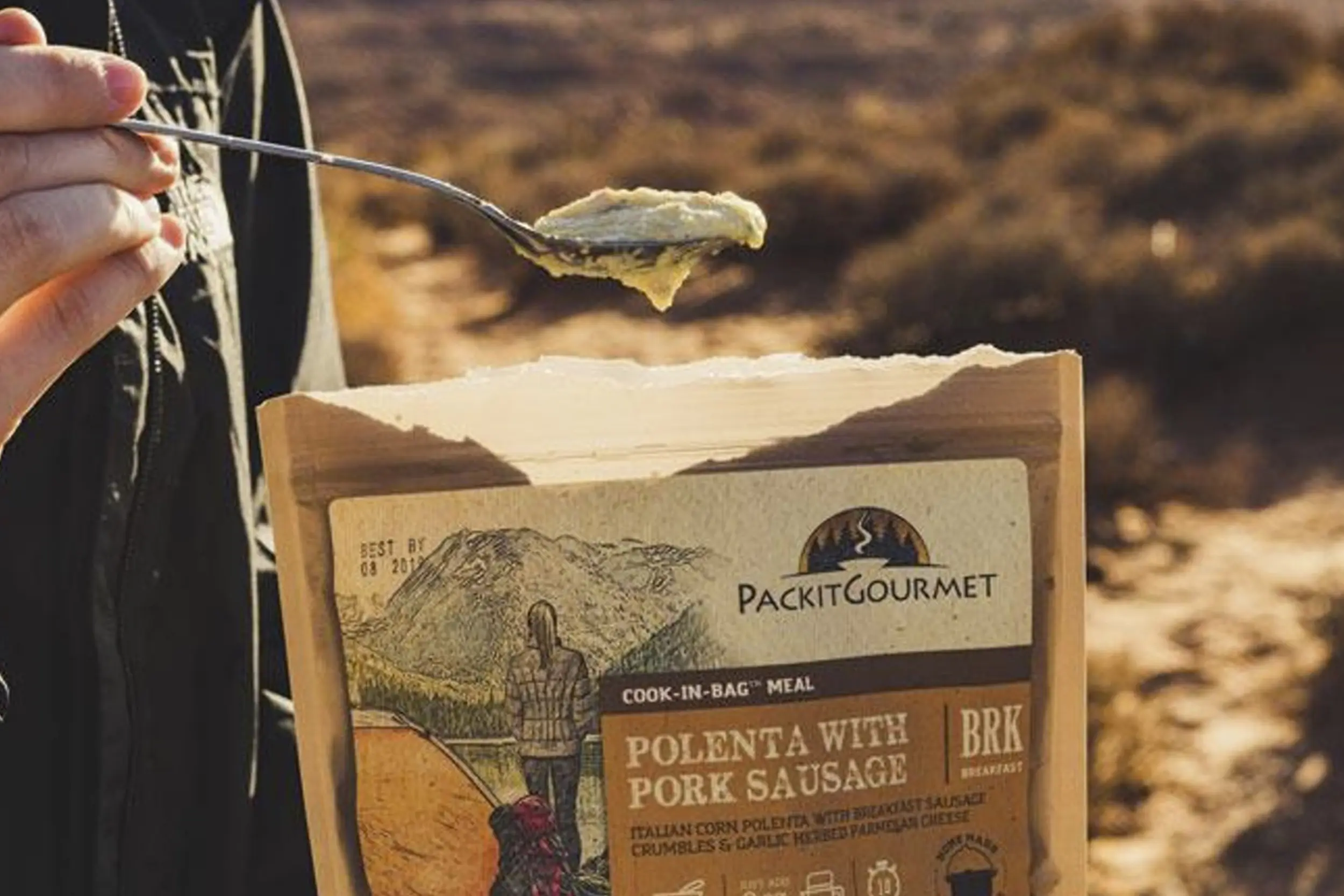 a man spoons food out of a pouch of packit gourmet food