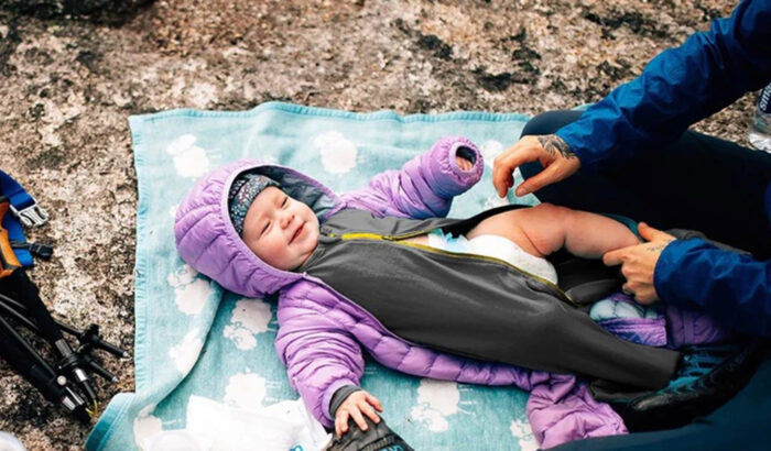 Giv'r Gloves A parent changes the diaper of a baby wearing a iksplor Baby Adventure Zippy