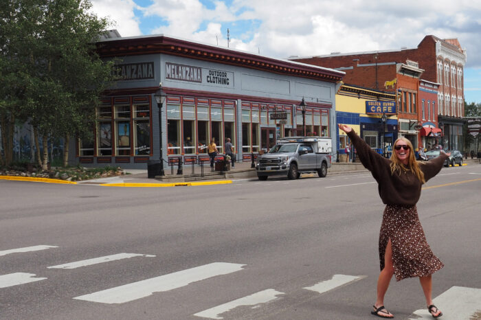 a woman stands on the street in front of the Melanzana store