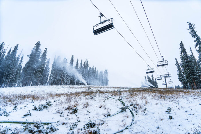 a chair lift with scant snow on the ground below it