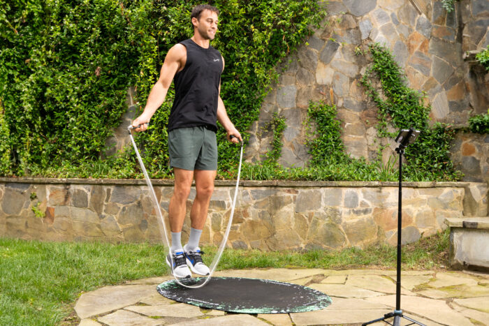 man jumping rope outside in front of ivy-covered wall
