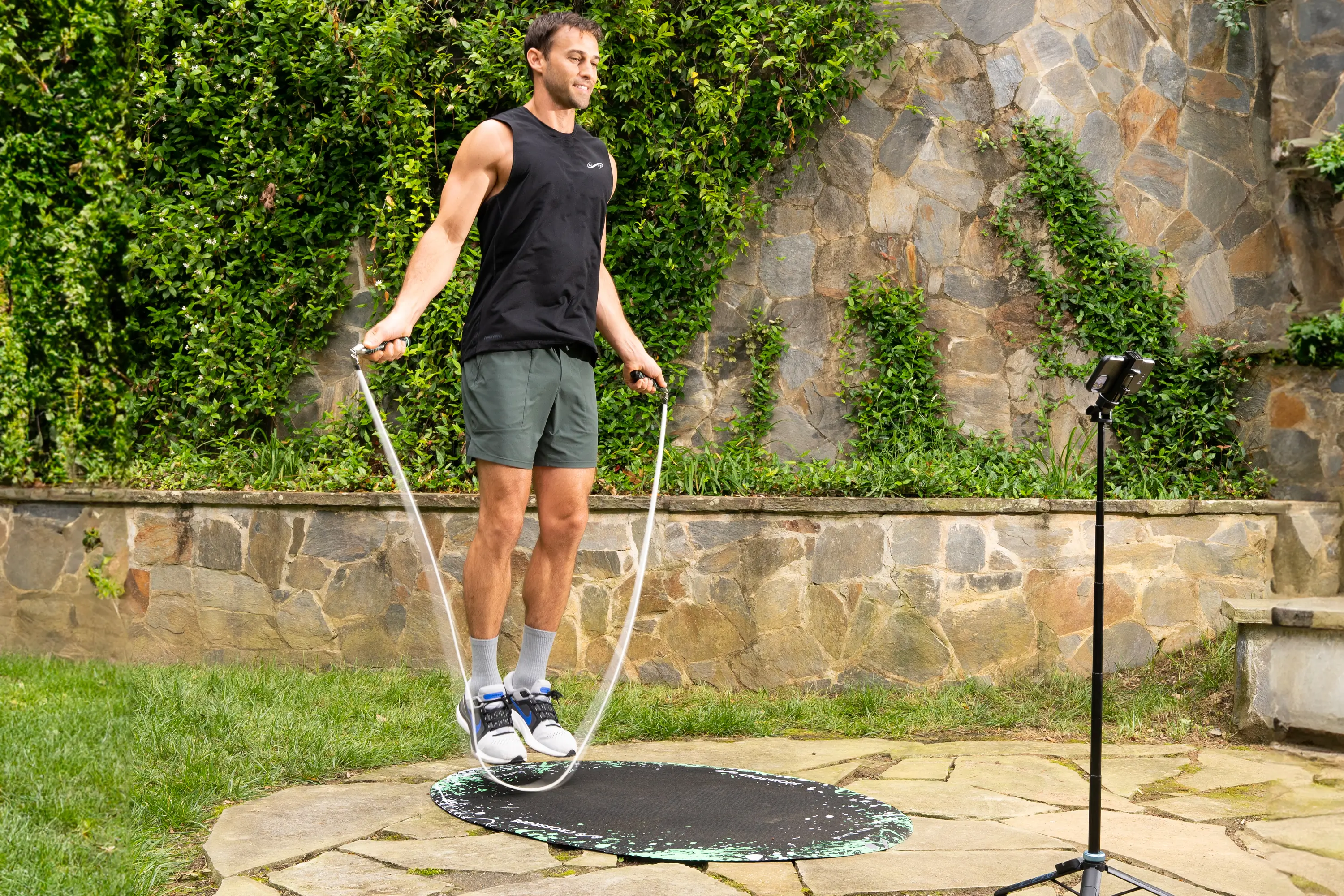 man jumping rope outside in front of ivy-covered wall