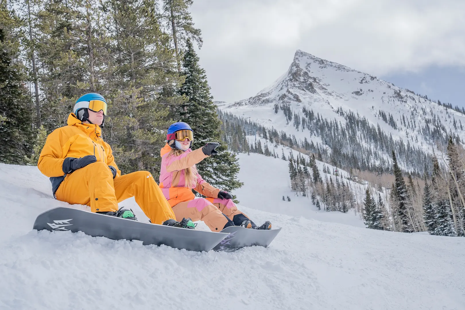 two snowboarders sitting on the edge of the run with Mt. CB in the background 