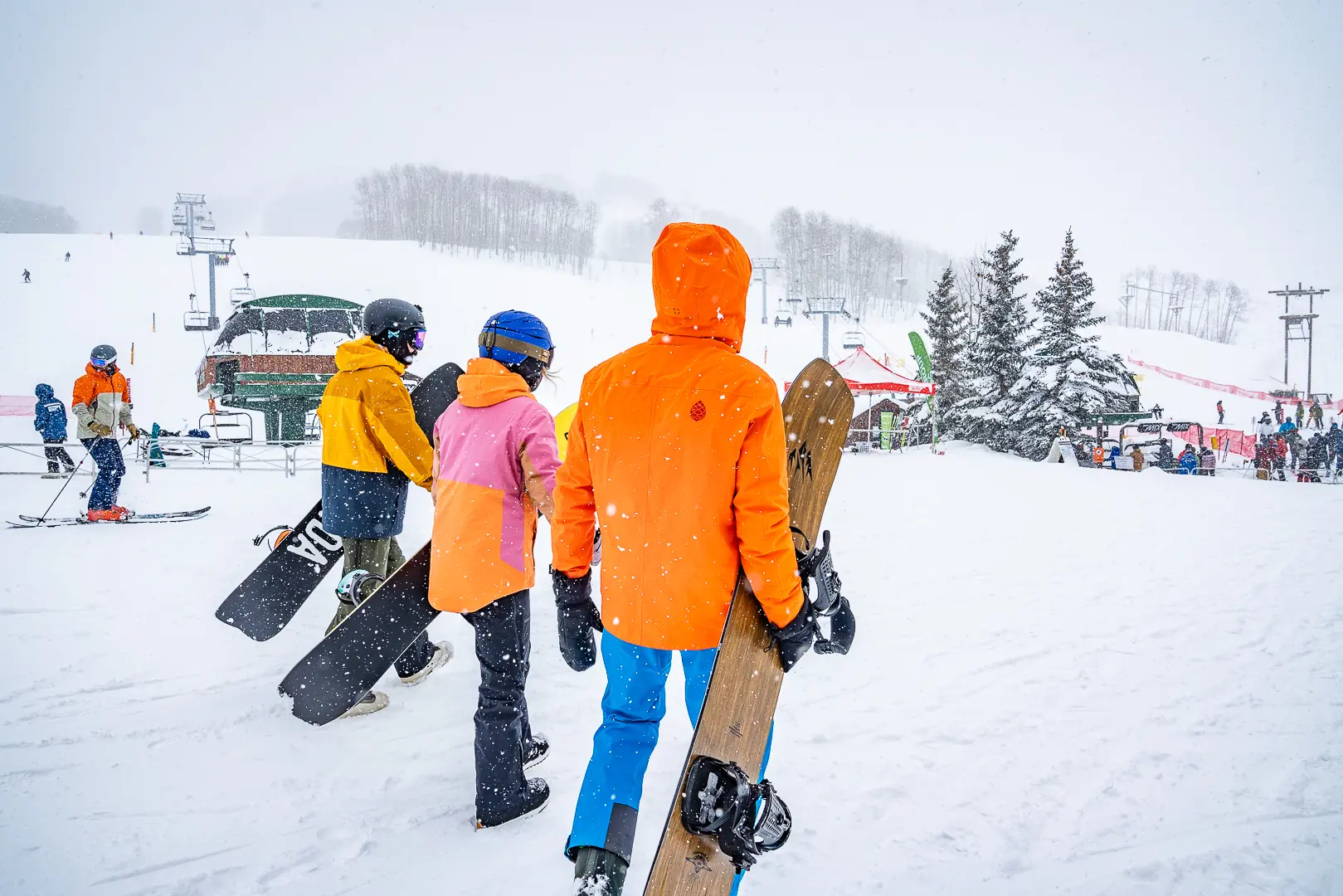 three snowboarders walking toward the lift