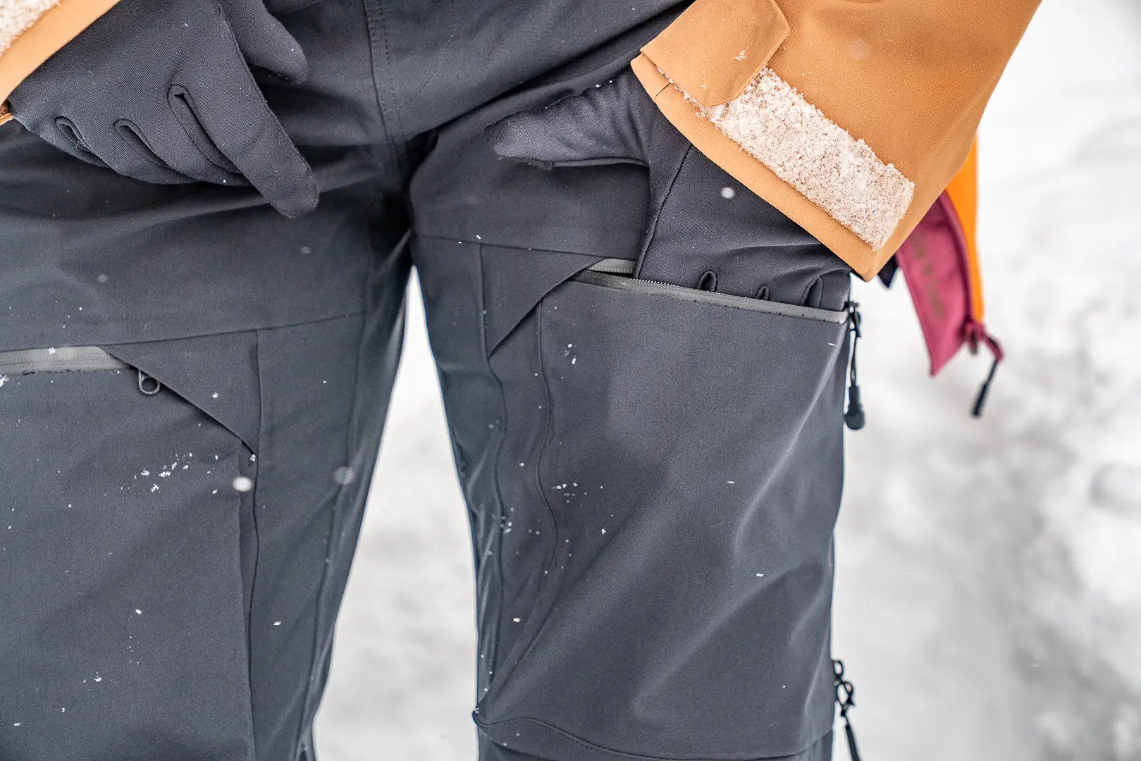reaching into thigh pocket of snow bibs with glove liner on