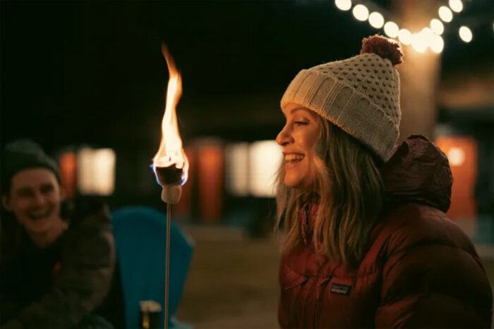 a woman blows out a flaming marshmallow