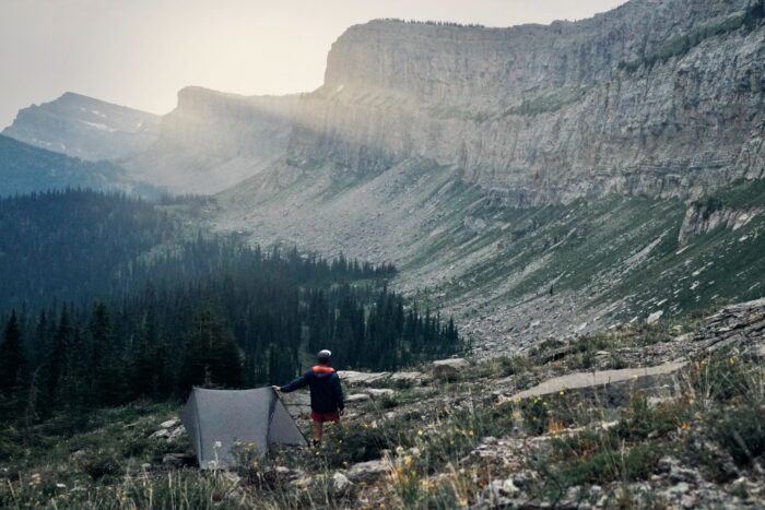 A man stands next to an ultralight tent at an overlook