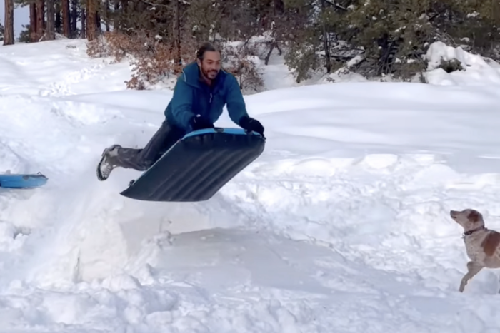 a man riding the adrenaline sled off a snow jump