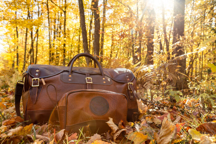 a leather duffel bag in a yellow forest