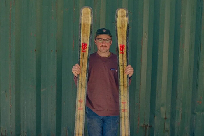 a man holds a pair of Romp Oso 105 skis