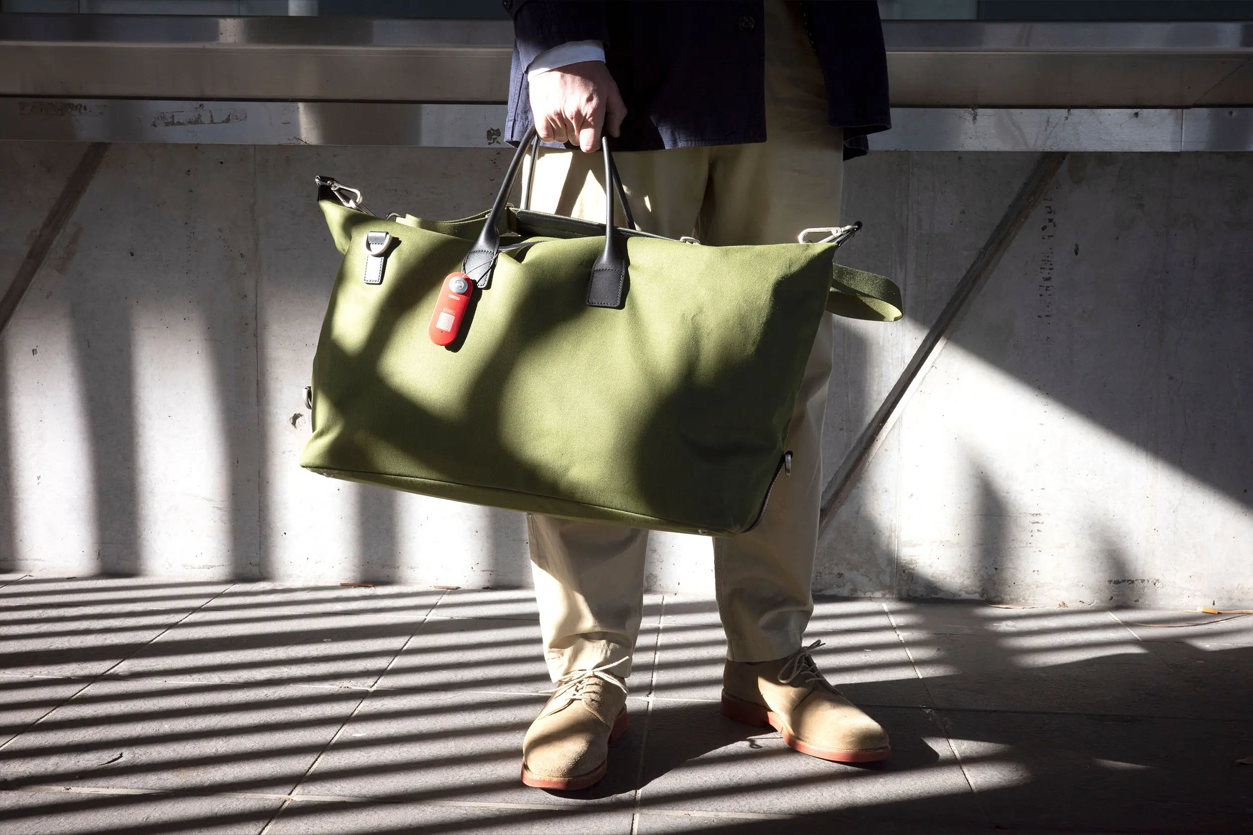 The Knog smart travel luggage tag on a green duffel