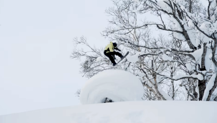 snowboarder Wolfgang Nyvelt in a yellow jacket boarding off a pillowy jump outside Hokkaido Japan