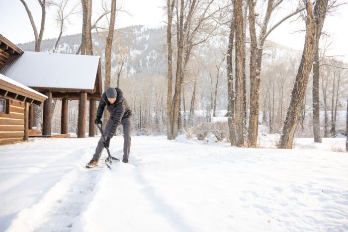 a man shovels snow outside a snowy colorado cabin