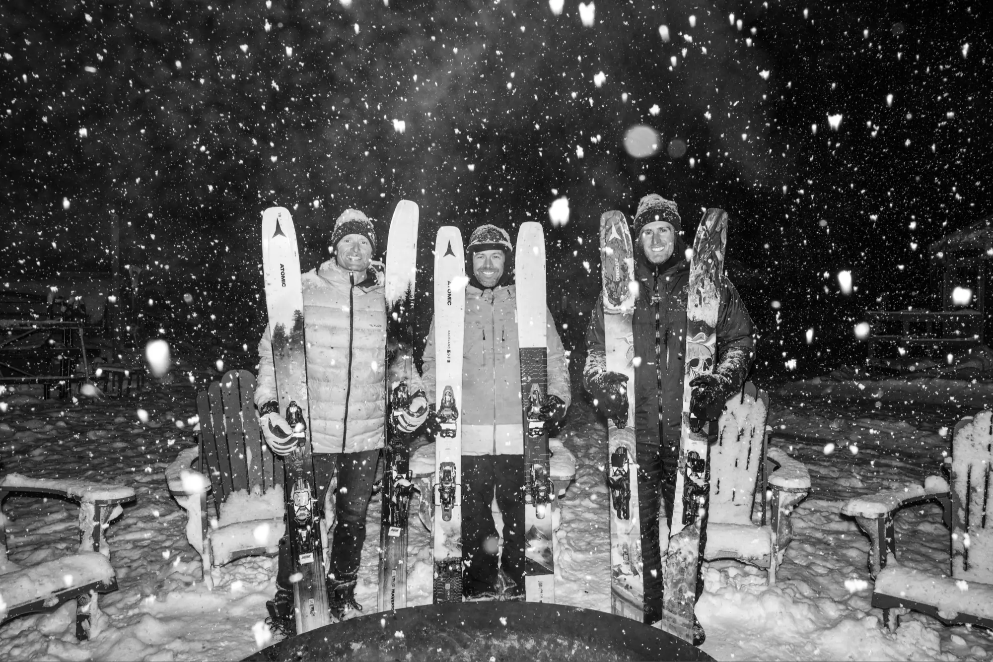 Three skiers holding Atomic skis
