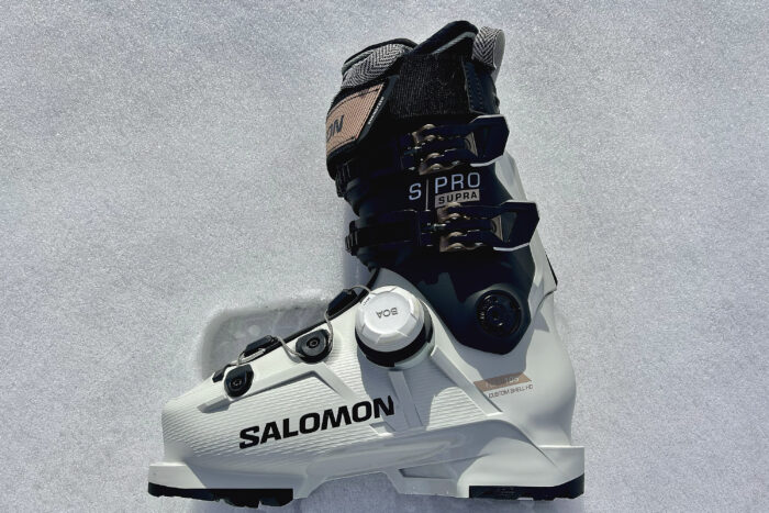 a profile of the white black and pink Salomon S/Pro Supra Women's BOA Ski Boot in the snow