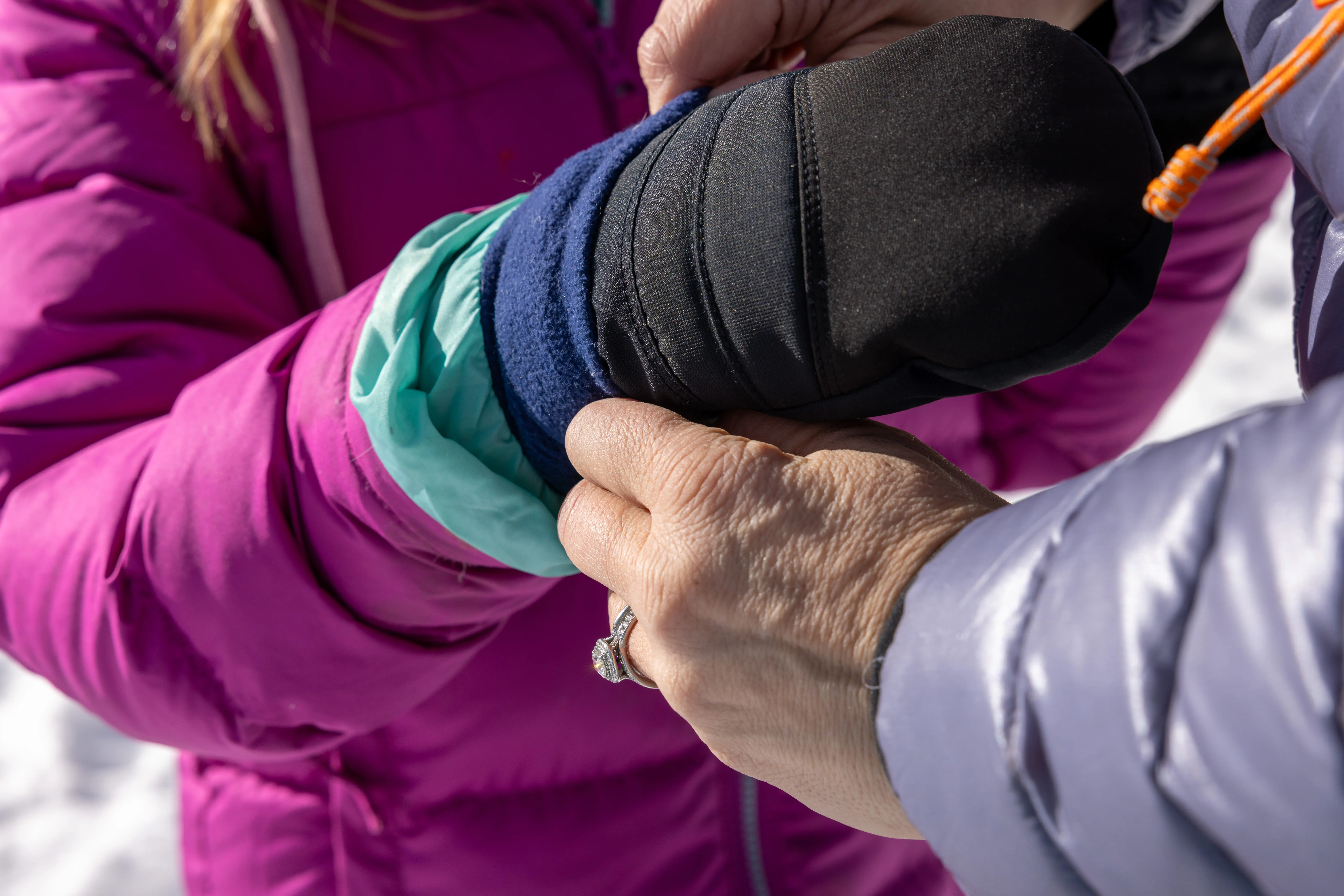 parent pulling jacket cuff over mitten