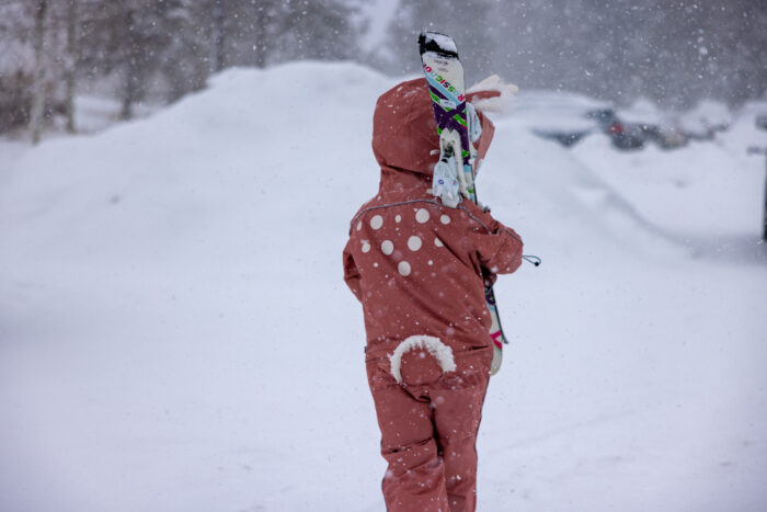 young girl carrying skis in parking lot 