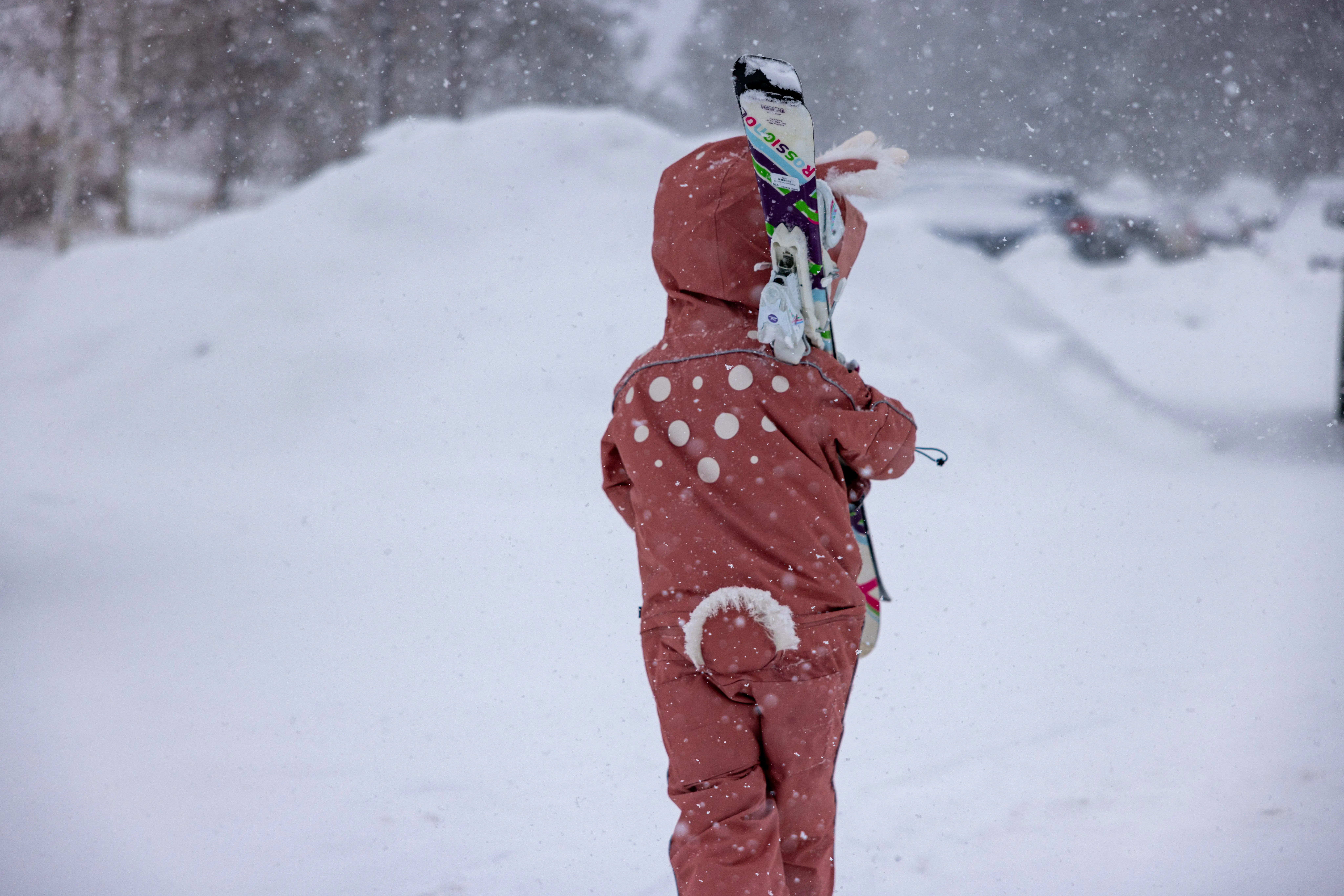 young girl carrying skis in parking lot