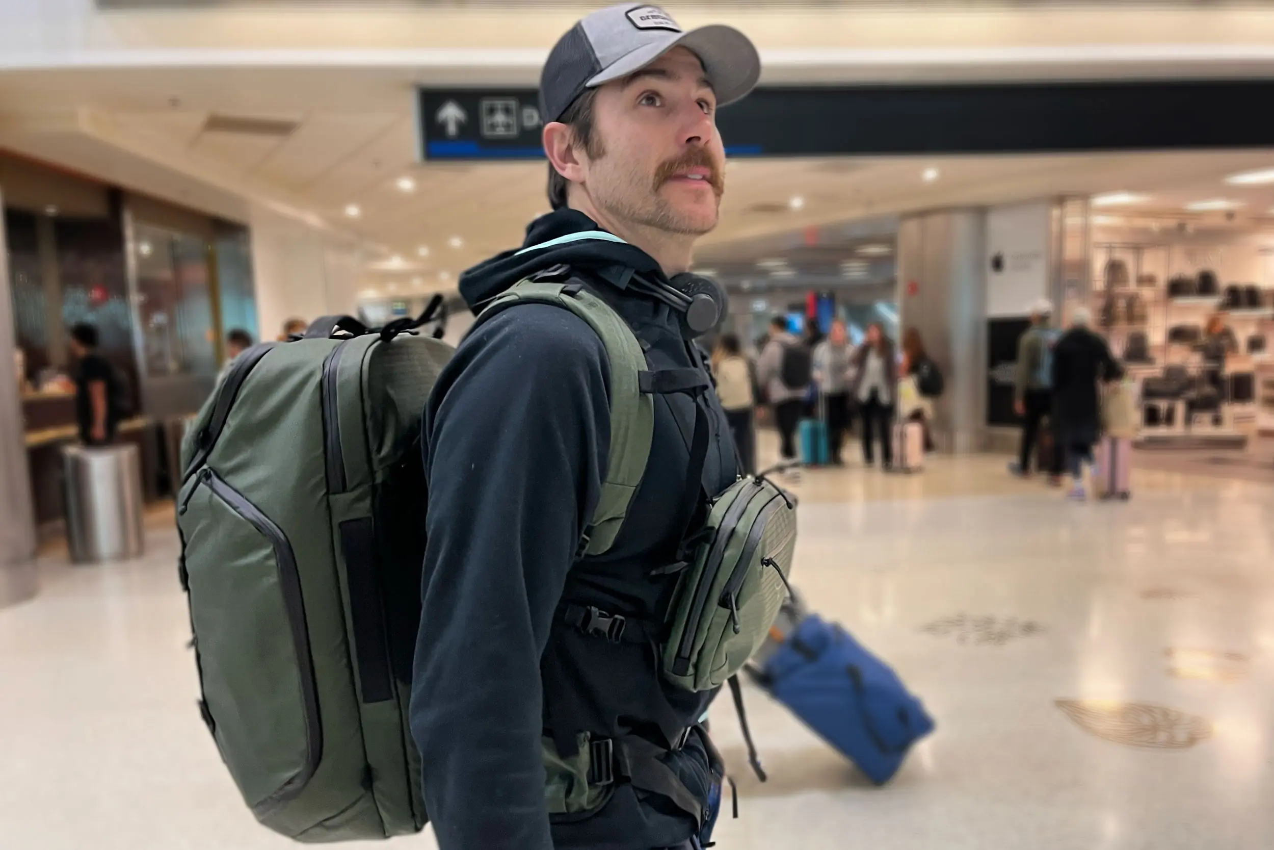 man wearing osprey archeon carry-on luggage kit in airport