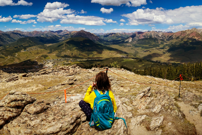 Young girl on a mountain with a backpack