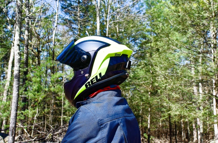 a profile of a motorcyclist wearing a motorcycle helmet in a forest 