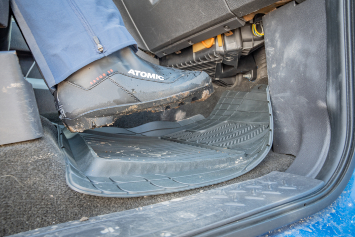 A muddy boot stepping onto a car floor mat