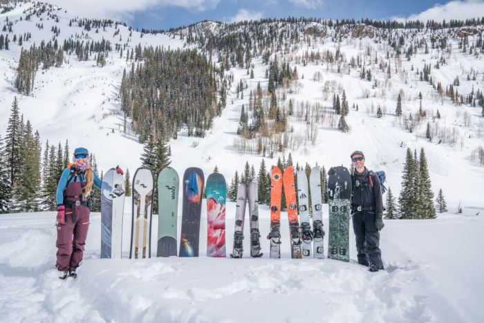 a lineup of splitboards in snow with two lead testers 