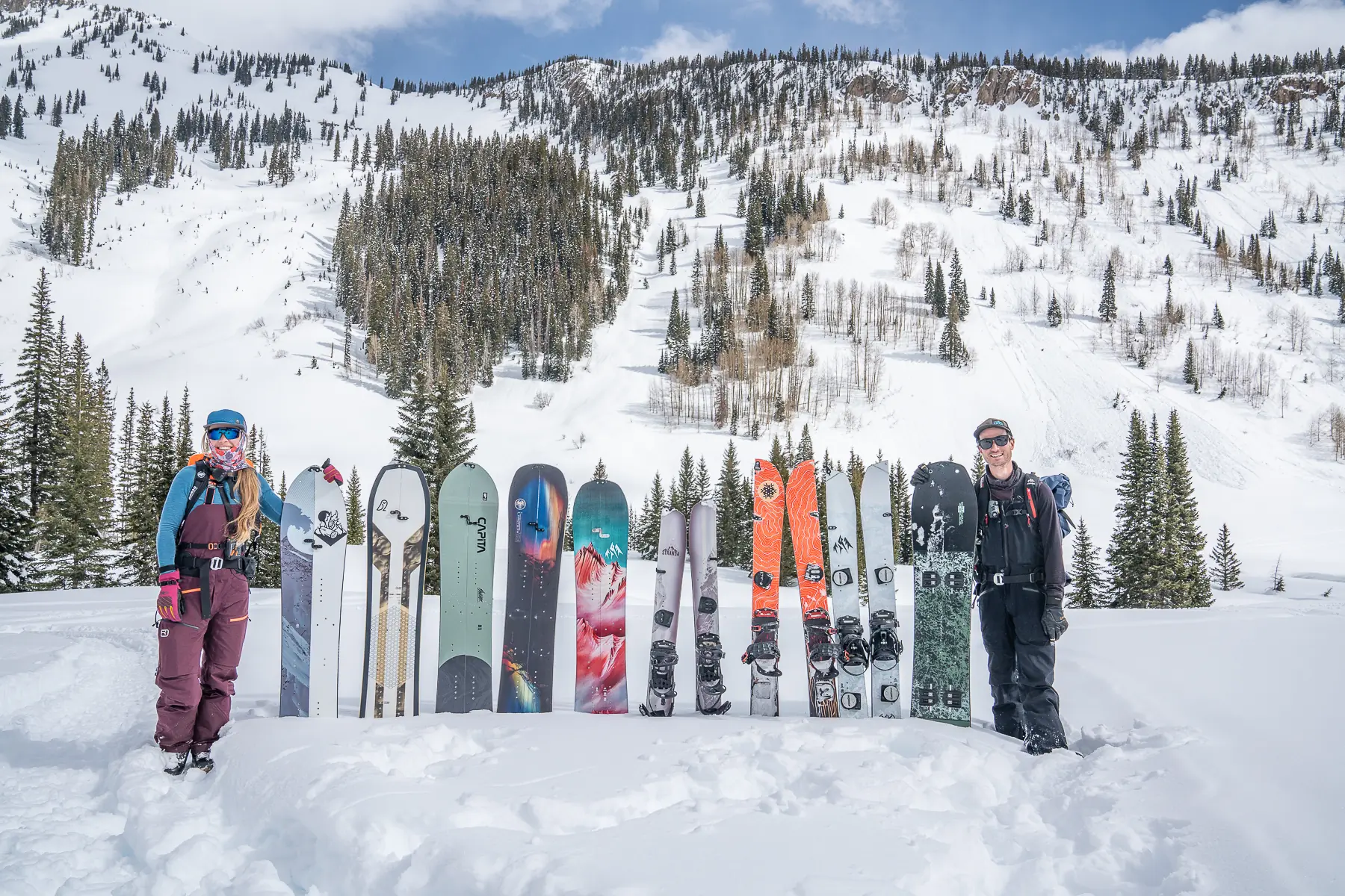 a lineup of splitboards in snow with two lead testers