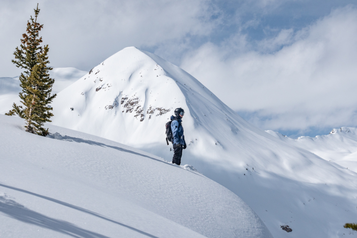 splitboarder standing at the top of a line with mountain backdrop 