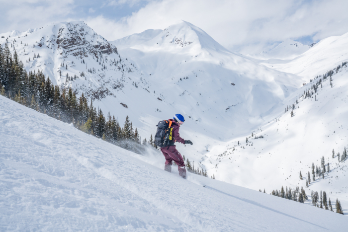 splitboarder descending on powdery slope with mountain backdrop 