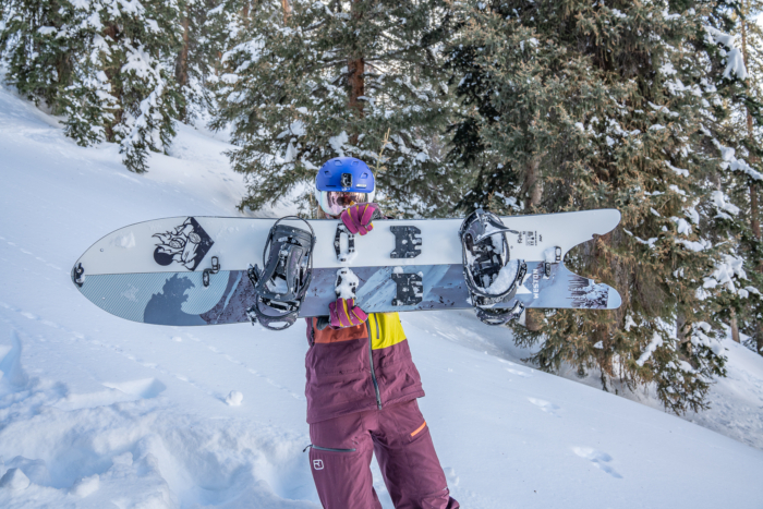 female splitboarder holding up board 