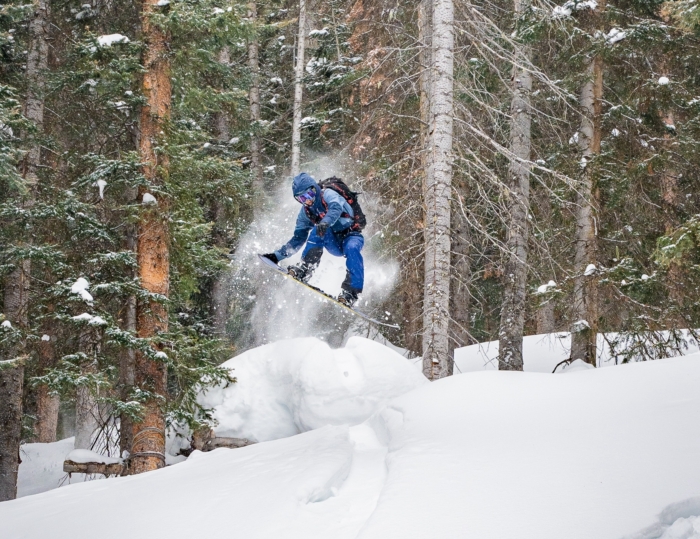 splitboarder hitting jump in trees 