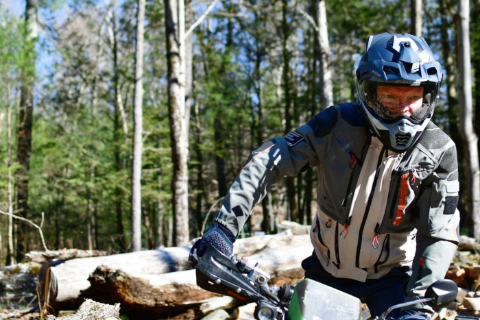 man standing in footpegs of adventure motorcycle bike in forest 