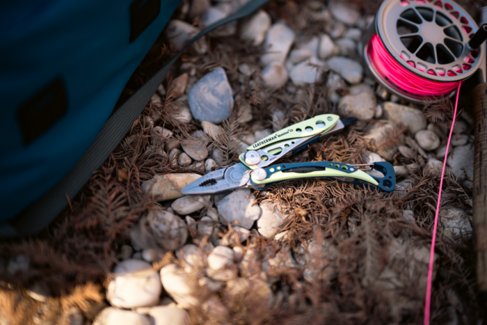 Leatherman Skeletool CX next to a neon pink fishing line on a reel