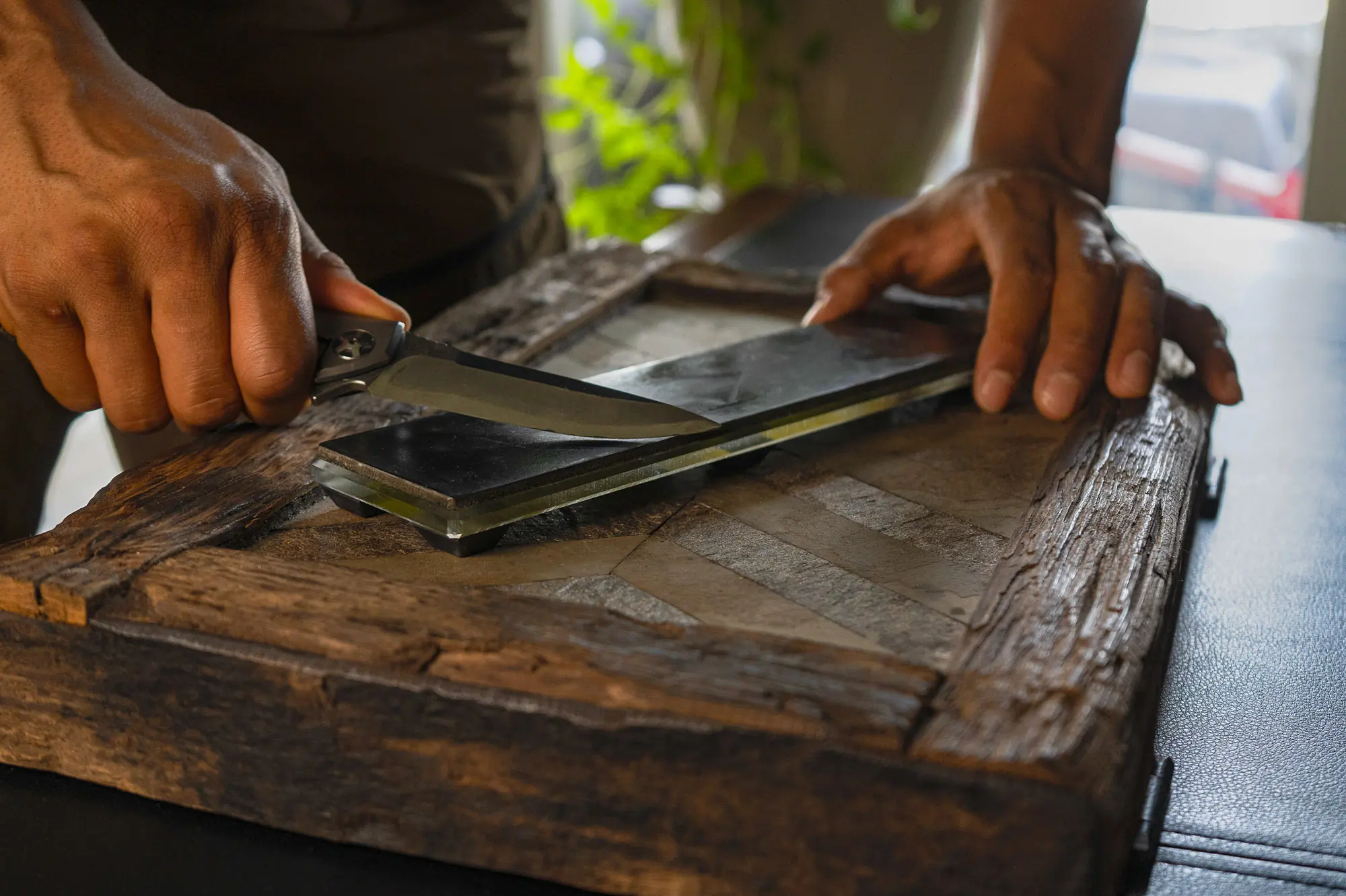 the author using a leather strop to maintain a blade edge on a tabletop