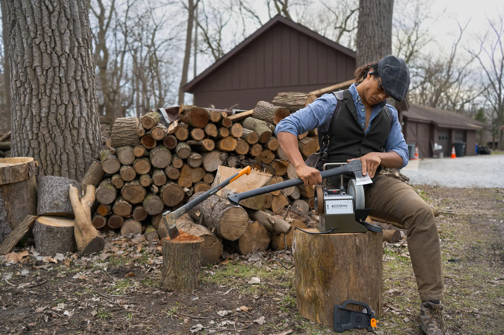 the author sharpening a splitting axe in a wood yard with a tormek electric sharpener