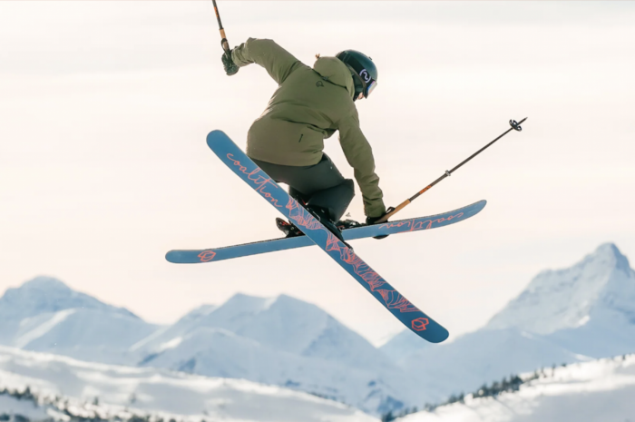 women sending it on a jump with a grab on Coalition Skis