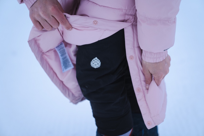 woman opening the Pike Lake II Long Jacket's snappable side panels