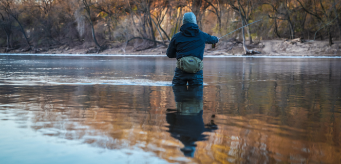 man fly fishing in water while wearing patagonia winter gear