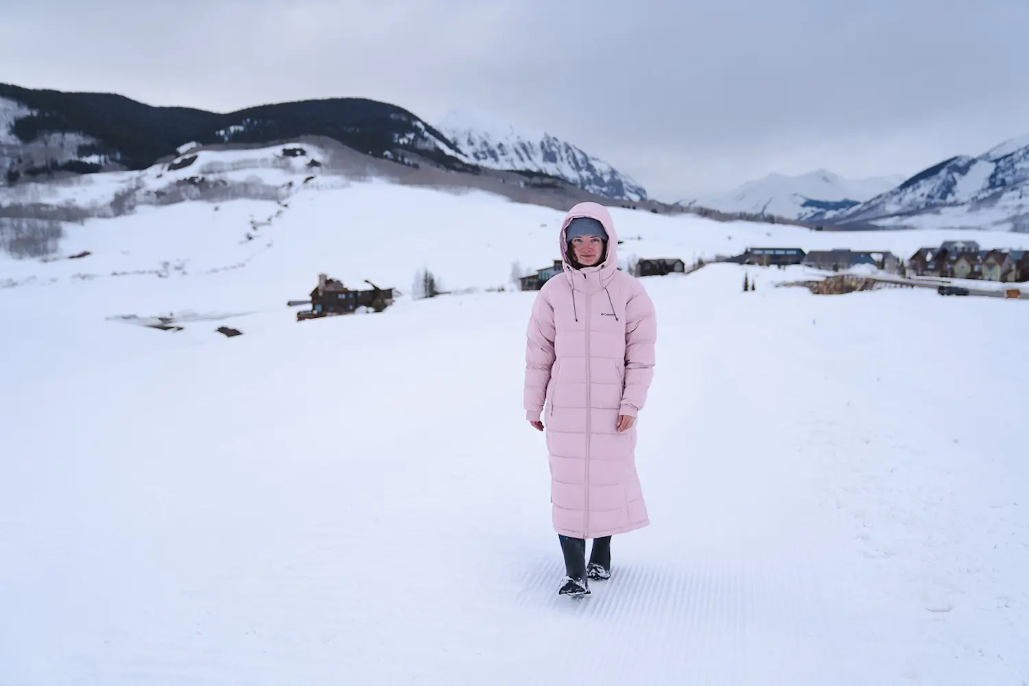 woman walking outside in a wintry mountainous landscape while wearing a long winter coat