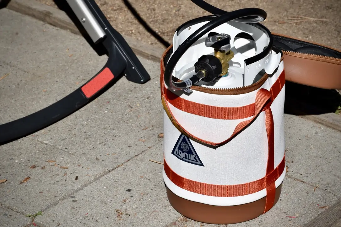 a close up view of the Ignik Gas Growler in action, fueling the Weber Traveler Gas Grill