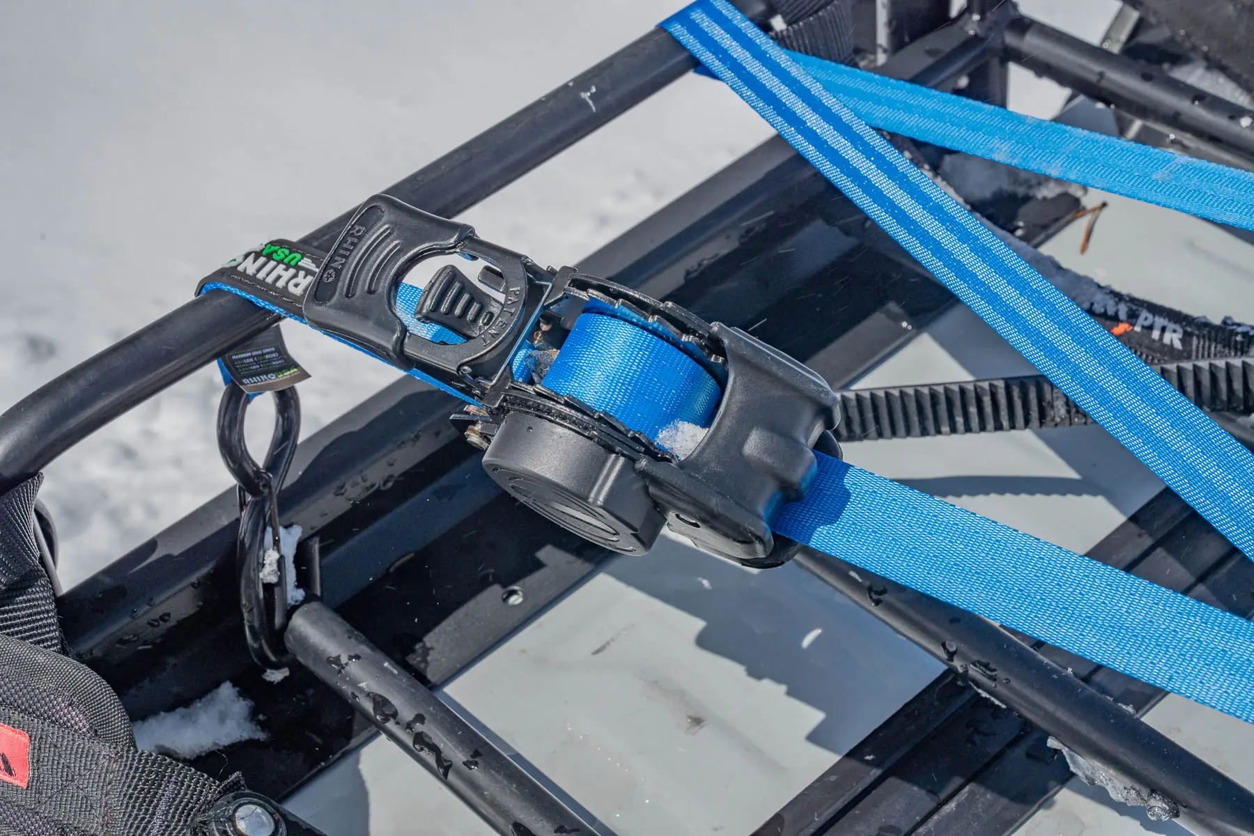 the Rhino Rack Retractable Ratchet Straps being used on a snowmobile rack 