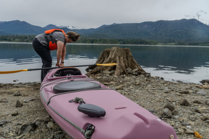 a paddler pulls the rotomolded Tsunami kayak across a rocky shore