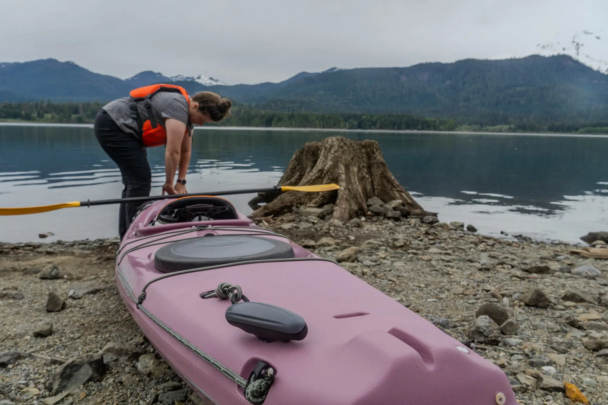 a paddler pulls the rotomolded Tsunami kayak across a rocky shore