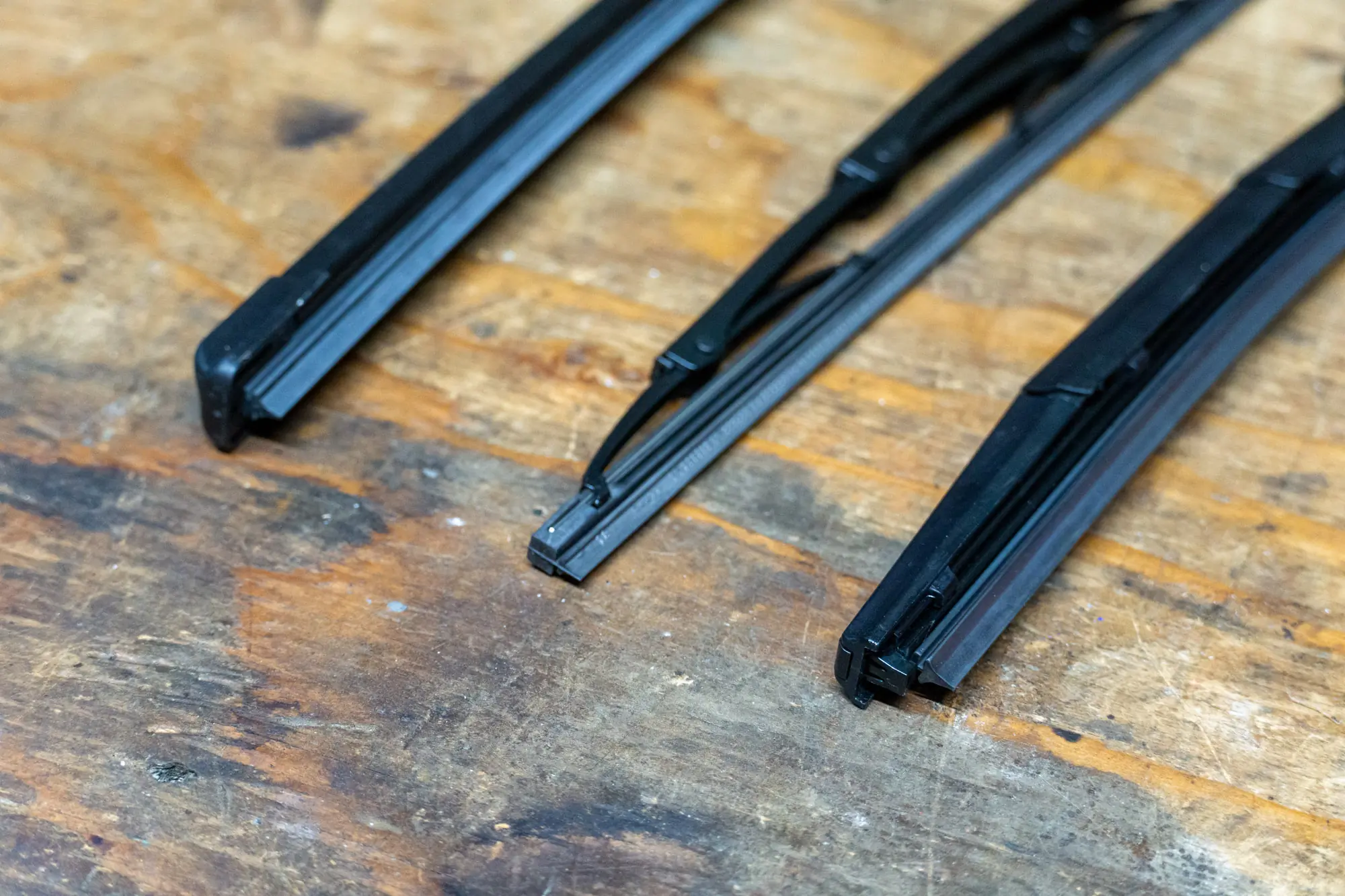 three sets of wipers laid on a work bench, detailing the different blade styles