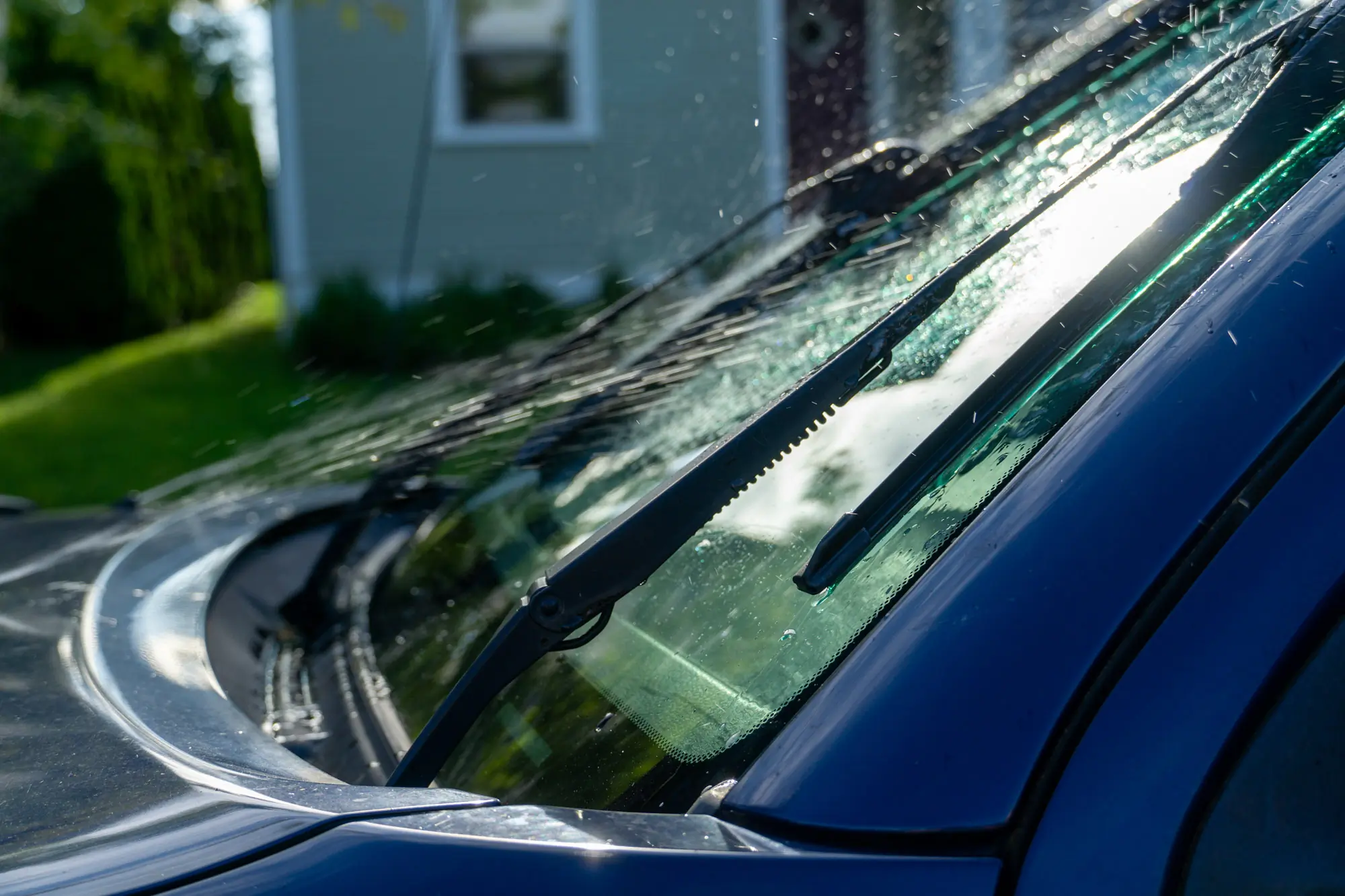 a set of wiper blades running as wiper fluid sprays on a window