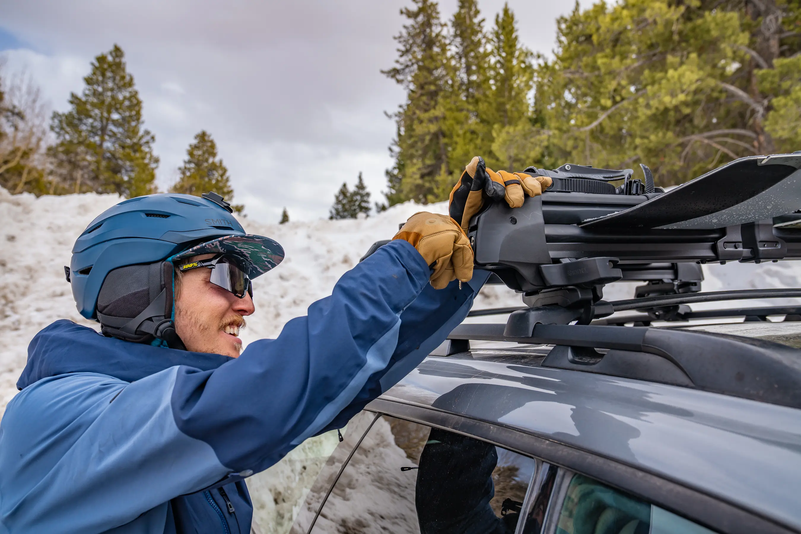 man turning key in lock on roof rack for skis and snowboards on top of car