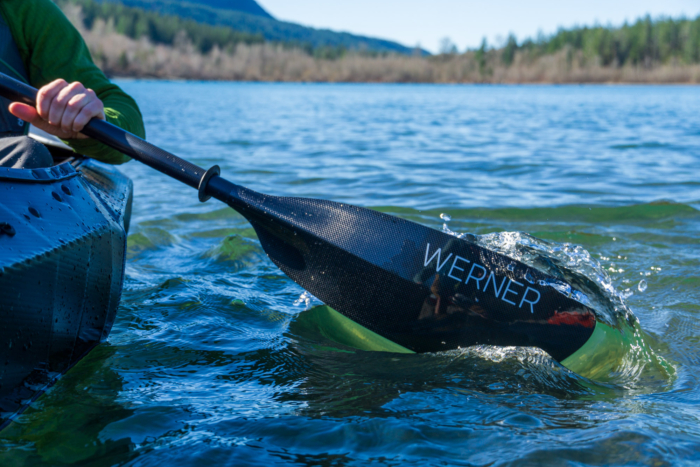A Werner Kalliste kayak paddle dips through the water as a kayaker makes a stroke