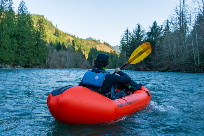 A packrafter in a red boat paddles the Werner Sherpa paddle, which has a broad paddle volume