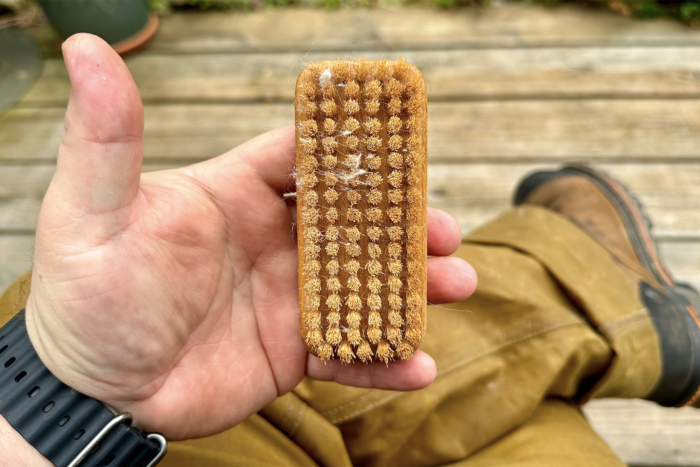 man holding filson single tin cloth pants gardner's nail brush